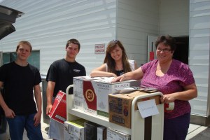 Delaware Division of Libraries receives 2,500+ books! Pictured, left to right, are Success Won't Wait volunteers Garrett Issel, Matt McNeill and Ashley McNeill with Kirkwood Highway Children's Librarian Elisabeth Simmons.